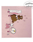 Baby shower card with a bear and baby items on a pink background, featuring 'It's a girl' text.