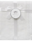 White baby blanket with a bow and 'Mother's Choice' label on a white background