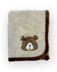 Folded blanket with a bear face patch on a white background