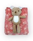 Plush bear toy on a pink floral blanket with a white background