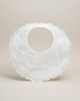 White baby bib with floral embroidery on a beige background