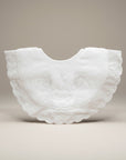 White embroidered baby bib on a beige background