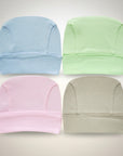 Four baby hats in blue, green, pink, and gray on a light gray background