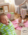 Two babies in a room with colorful blankets and a 'Mother's Choice' bag.