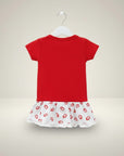 Red top and white skirt with red lip prints on a hanger against a beige background