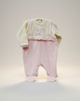 Baby outfit with pink pants and cream sweater on a light background