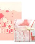 Pink children's blanket with house and tree design on a white background