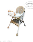 Beige and white high chair with accessories on a white background, featuring 'Mother's Choice' branding.
