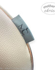 Close-up of a beige leather product with a gray strap featuring 'mother's choice' branding on a white background.