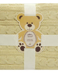 Beige textured blanket with a teddy bear tag featuring 'Mothercare' branding.