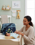 Mothers Choice Fun Daypack Navy with embroidered animals and plaid pattern. A mom and baby are in the background.