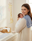 Stork And Baby blue bamboo burp cloths with a white leaf pattern, worn by a mother holding her baby.