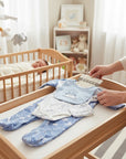 Stork And Baby 5 piece starter pack with blue dino print, 100% cotton interlock, includes bodysuit, footed pajamas, and bib.