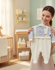 Stork And Baby light blue velour baby growers with cream footies and pram embroidery. Features faux suspenders and ruffle trim.