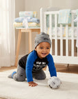 Stork And Baby boys 3 piece set: black & blue long sleeve top, grey monster print pants & hat. Baby crawling.
