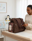 Stork And Baby brown check diaper bag with a woman pointing to it, featuring a bottle holder.