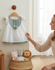 Stork And Baby white cotton linen dress with sage green accents, eyelet details, and floral embellishment.