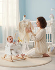 Stork And Baby cream striped baby romper with bowtie detail, 0-9 months. Woman holding romper near baby.