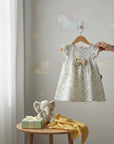 Stork And Baby Girls white floral print dress with yellow bow detail and flutter sleeves.