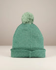 Stork And Baby green knit pom pom beanie for babies, perfect for winter outings and cozy cuddles.