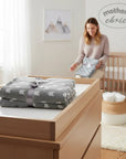Stork And Baby Mother's Choice grey fleece baby receiver blanket with white arrow pattern, folded on a wooden dresser.