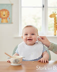 Stork and Baby white linen/cotton blend infant bib with embroidered floral and leaf design, perfect for feeding.
