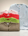 Stork And Baby light blue, pink, red, green, and tan infant jerseys made of soft knit fabric with button closures.
