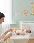 Stork And Baby white infant socks with a bow detail, being put on a baby by a mother.