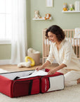 Stork And Baby Mothers Choice 3-in-1 travel bed and diaper bag in red and white, set up in a nursery for a baby.