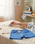 Stork And Baby beige 2-piece muslin set with carrot print top and blue shorts. Includes wooden toy.