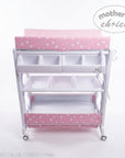 Stork And Baby pink baby bath caddy with star pattern, storage shelves, and changing mat on a white background
