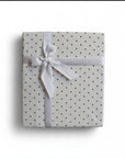 Stork And Baby Mothers Choice white cotton jersey baby wrap with black polka dots, tied with a white ribbon gift bow.