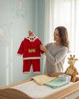 Stork And Baby red coral fleece tracksuit with "Love" embroidery and white trim. A woman holds it up.