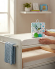 Stork And Baby 3 pack of turtle themed baby hooded towels and bath toys on a white changing table