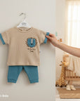 Stork And Baby beige waffle knit 2-piece set with blue trim and a lion graphic on the chest.