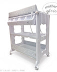 Stork And Baby white baby bath caddy with star pattern changing mat, storage shelves, and drainage hose on wheels