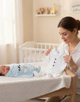 Stork And Baby white 5-piece 0-3 month cotton baby starter pack with buttons and bow tie. Newborn swaddled in blue.