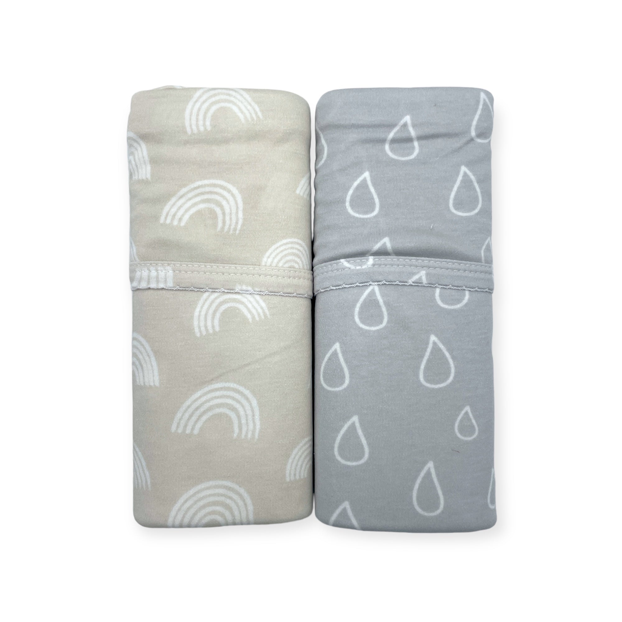Two folded towels with rainbow and raindrop patterns on a white background