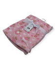 Pink baby blanket with teddy bear pattern and white tag on a white background