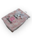 Pink blanket with white paw prints and text, featuring a tag, on a white background