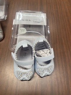 Pair of baby shoes in clear packaging on a wooden surface