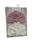 Two baby turban hats on a wooden display card with a hook.