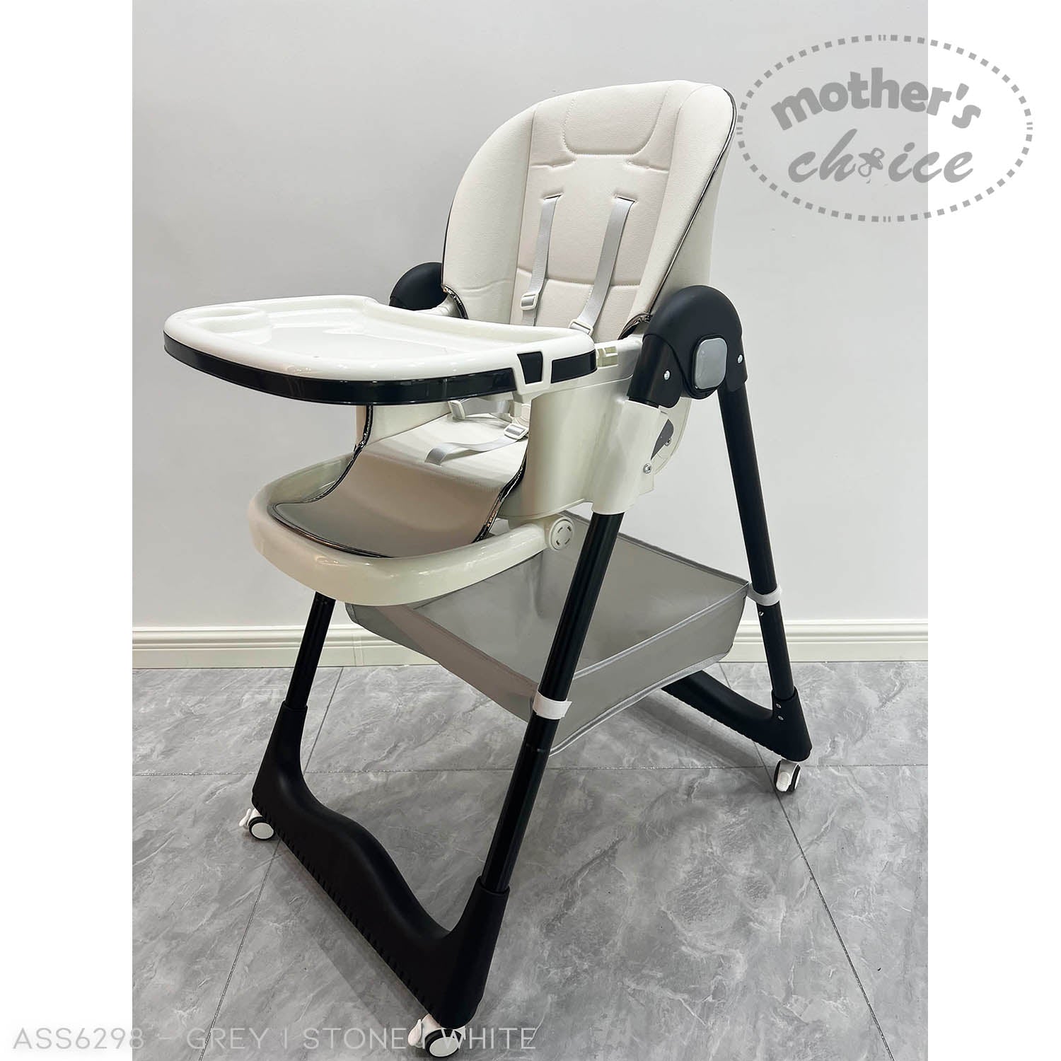 Child's high chair with tray on a gray floor, branded 'Mother's Choice'.