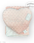 Heart-shaped pink pillow with 'baby' embroidery and a tag on a white background