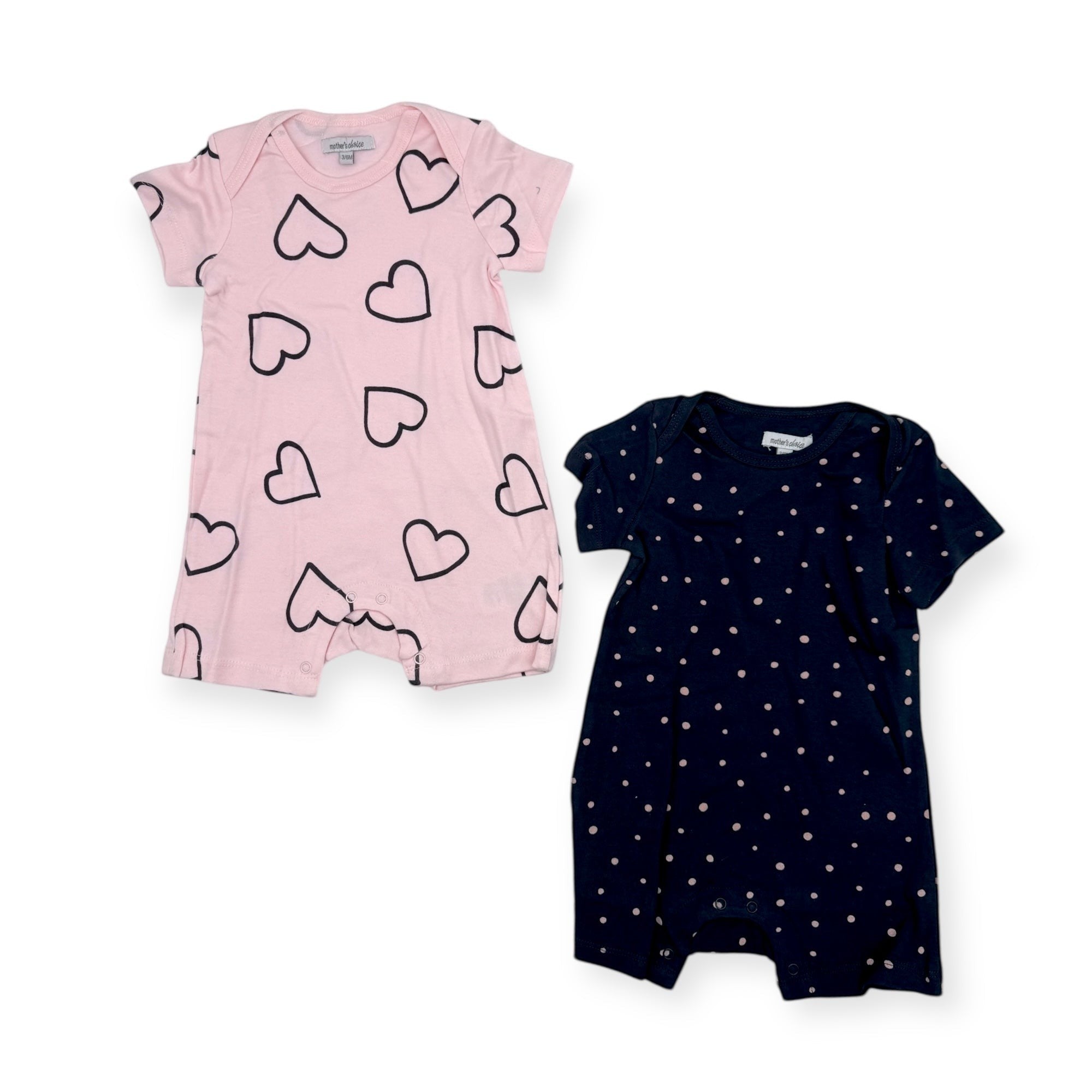 Two baby rompers, one pink with black heart patterns and one navy with white dot patterns, on a white background.
