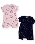 Two baby rompers, one pink with black heart patterns and one navy with white dot patterns, on a white background.
