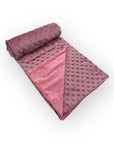 Folded pink blanket with textured surface on a white background