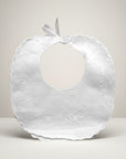 White baby bib with floral embroidery on a light gray background