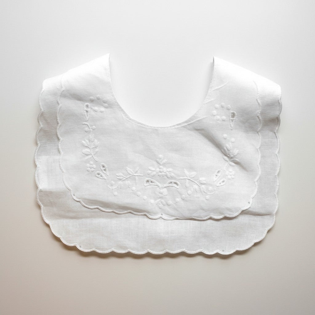 White scalloped bib on a light gray background