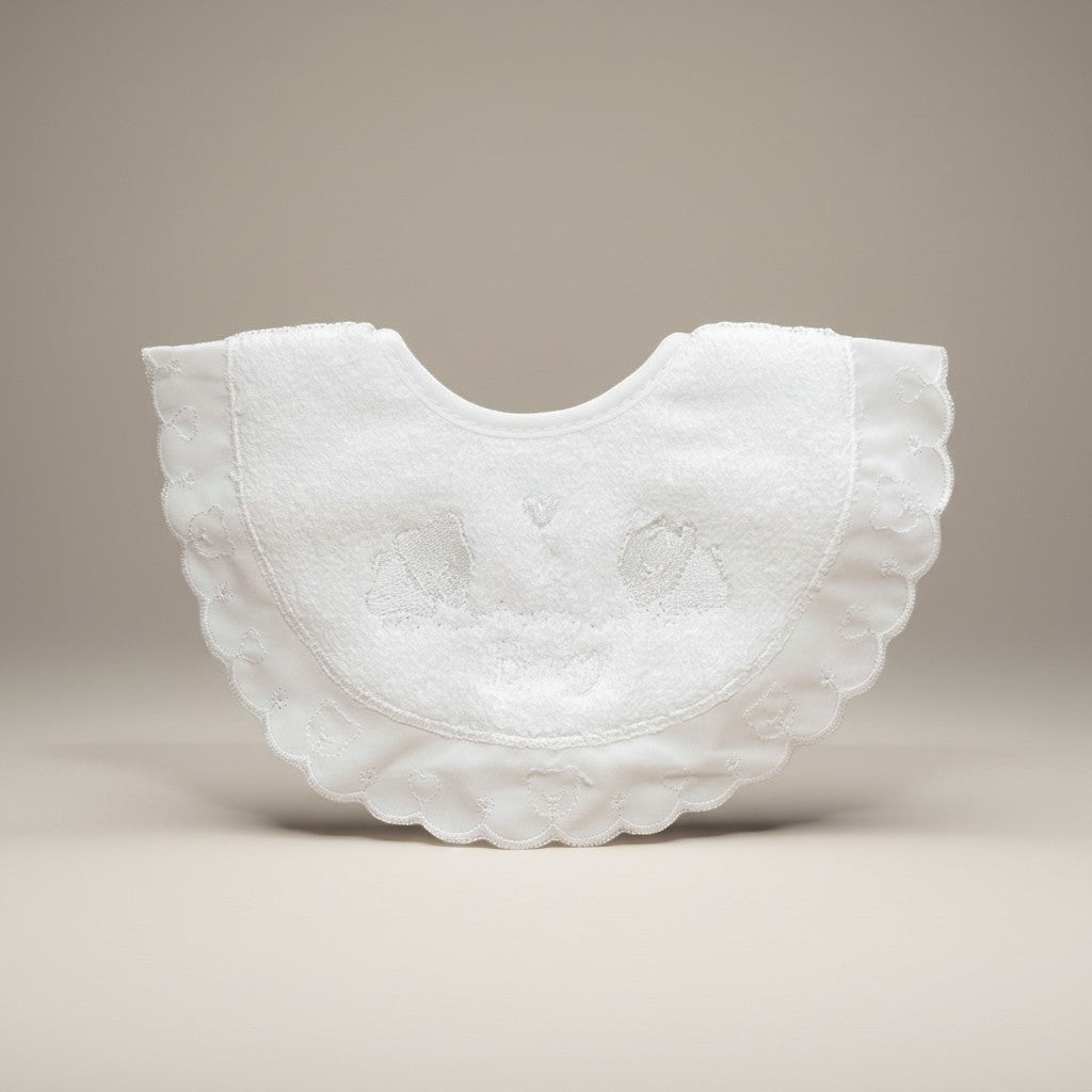 White embroidered baby bib on a beige background